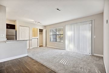 Raleigh apartment for rent - A spacious living room with a grey carpet and a window with white blinds.