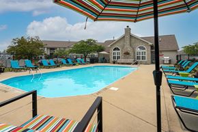 Pataskala apartment for rent - A pool with a striped umbrella and chairs.