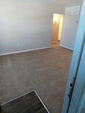 Poquoson apartment for rent - A room with a carpeted floor and a doorway leading to another room.
