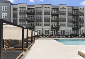Clover apartment for rent - A large pool area with lounge chairs and umbrellas in front of apartment buildings.