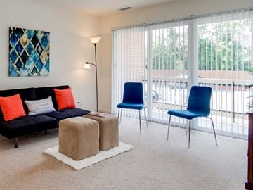 Williamsburg apartment for rent - A living room with a black couch, two blue chairs, and a painting on the wall.