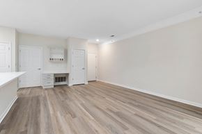 Columbus apartment for rent - an empty living room and kitchen with white walls and wood flooring  at The Charleston, Columbus