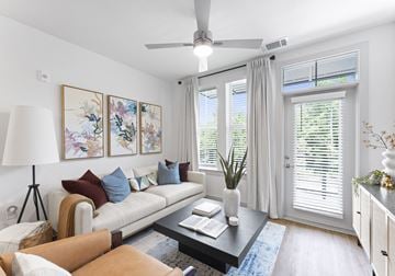 Clover apartment for rent - A living room with a white couch, a brown leather chair, a coffee table, and a painting on the wall.