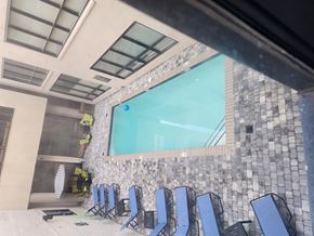 Richmond apartment for rent - A pool area with blue chairs and a stone wall.