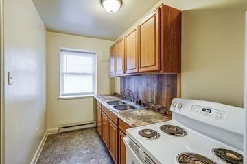 Raleigh apartment for rent - A small kitchen with a white stove and wooden cabinets.