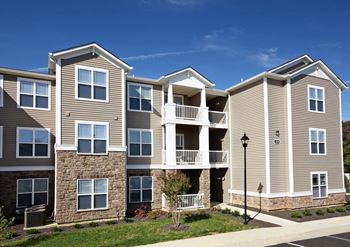 An apartment building with tan siding and a tan brick wall