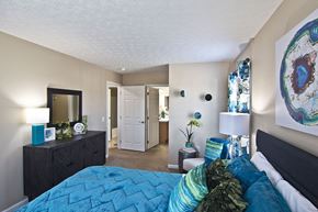 Pataskala apartment for rent - A bedroom with a blue bedspread and a painting on the wall.