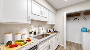 Raleigh apartment for rent - a kitchen with white cabinets and a wooden cutting board with vegetables on it