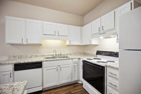 Raleigh apartment for rent - a kitchen with white cabinets and black appliances and white counter tops