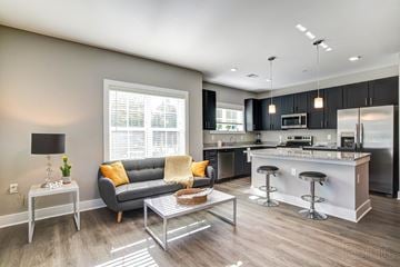 Wilmington apartment for rent - A modern kitchen and living room with a grey couch and a coffee table.