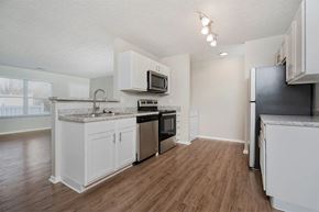Columbus apartment for rent - A kitchen with white cabinets and a black fridge.