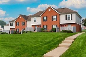 Marysville apartment for rent - A red brick house with a white fence and a green lawn.
