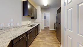 Apex townhouse for rent - A kitchen with dark brown cabinets and a granite countertop.