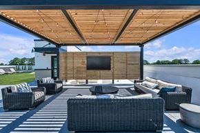 Newport News apartment for rent - A patio with a television and furniture under a wooden roof.