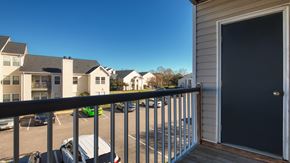Virginia Beach apartment for rent - A balcony with a black door and a view of a parking lot with cars.