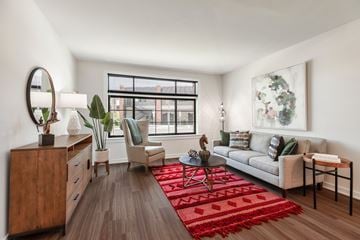 Frederick apartment for rent - A living room with a red rug and a white couch.