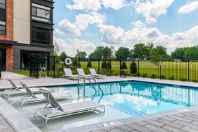 Frederick apartment for rent - A pool with lounge chairs and a building in the background.