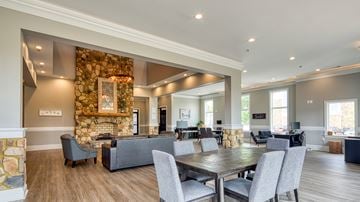 Lynchburg apartment for rent - A modern living room with a stone fireplace and a dining table set up.