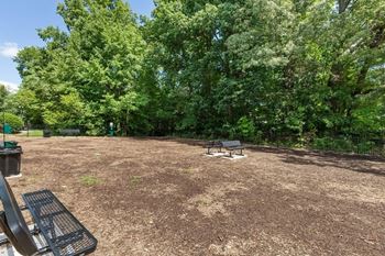 A picnic area with a grill and benches in a park