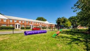 Dundalk apartment for rent - A playground with a purple slide and a red car parked in front of a brick building.