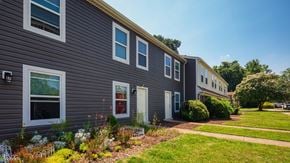 Richmond apartment for rent - A grey building with white windows and a green lawn in front.