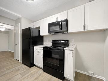 Raleigh apartment for rent - A black refrigerator and oven in a kitchen with white cabinets.