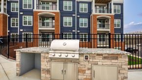 Midlothian apartment for rent - an outdoor kitchen with a stone island with a gas grill at The Bella at Westchester, Midlothian, 23113