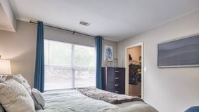 Newport News apartment for rent - a bedroom with a large window and a bed with blue curtains