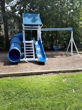 Poquoson apartment for rent - A blue slide and chair are in the foreground of a playground.