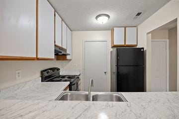 Rock Hill apartment for rent - A kitchen with a black refrigerator and a marble countertop.