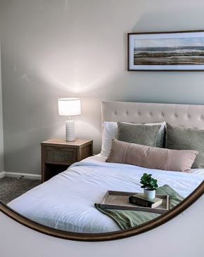 Hampton apartment for rent - A bedroom with a bed, a nightstand with a lamp, and a painting on the wall.
