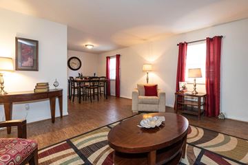 Newport News apartment for rent - A living room with a wooden table and chairs, a sofa, and a rug.