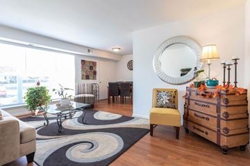 Newport News apartment for rent - A living room with a yellow chair and a wooden chest of drawers.