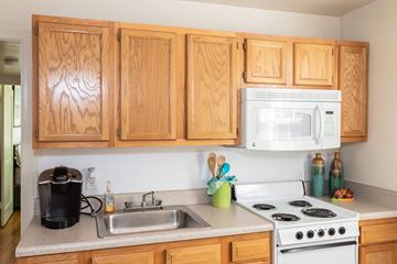 Newport News apartment for rent - A kitchen with wooden cabinets and a white stove top oven.