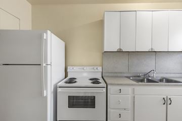 Raleigh apartment for rent - A white refrigerator is in a kitchen with white cabinets and a white stove.