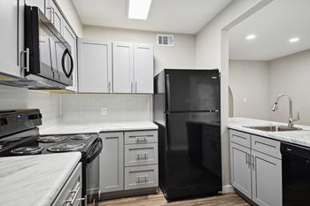 An empty kitchen with white cabinets and black appliances