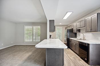 A kitchen with black appliances and a marble counter top