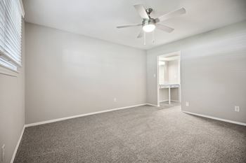 An empty room with carpet and a ceiling fan