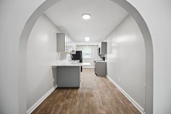 A kitchen and living room with white walls and wood floors