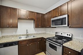 Carthage apartment for rent - A kitchen with brown cabinets and a black stove top oven.