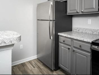 A kitchen with white cabinets and a stainless steel refrigerator