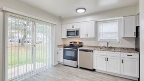 White Marsh townhouse for rent - a kitchen with white cabinets and a sliding glass door