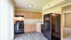 Richmond apartment for rent - A black refrigerator is in a kitchen with wooden cabinets.