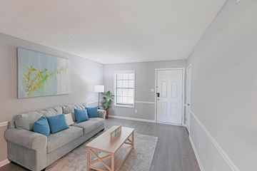 Kernersville apartment for rent - A living room with a grey couch and a painting on the wall.