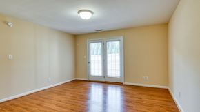 Forest apartment for rent - the living room of an empty house with wood floors and a door to a balcony