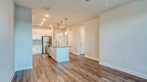 Midlothian apartment for rent - an empty living room with a kitchen with a sink and refrigerator at The Bella at Westchester, Midlothian, VA