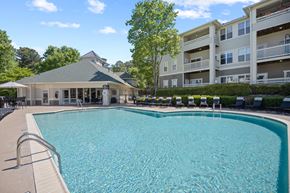 Raleigh apartment for rent - A large swimming pool with a diving board and a building in the background.
