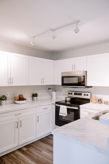 Sunbury apartment for rent - A kitchen with white cabinets and a black stove top oven.