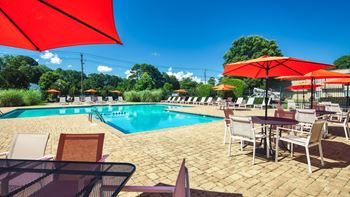 A swimming pool with tables and chairs and umbrellas