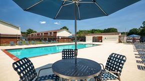 Richmond apartment for rent - A table with chairs and an umbrella is in front of a pool.